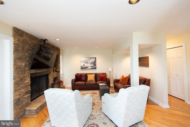 living room with a stone fireplace and light hardwood / wood-style flooring