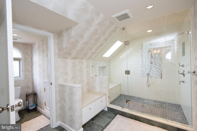 bathroom featuring tile patterned flooring, a skylight, a shower with shower door, and toilet