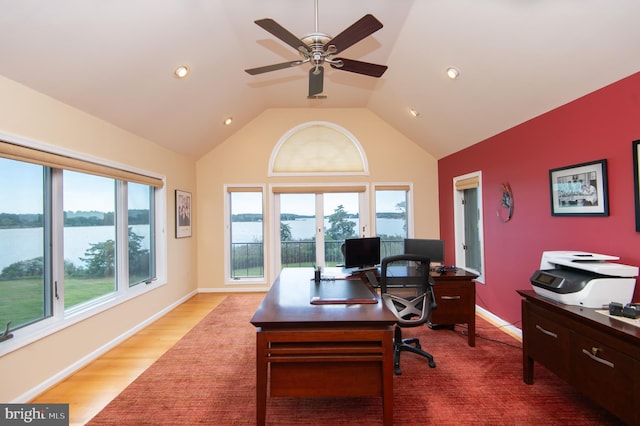 home office with ceiling fan, a water view, hardwood / wood-style flooring, and lofted ceiling