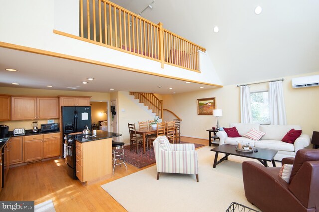 living room featuring a high ceiling, a wall unit AC, and light hardwood / wood-style floors