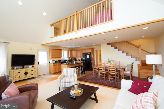 living room with a towering ceiling and light hardwood / wood-style flooring