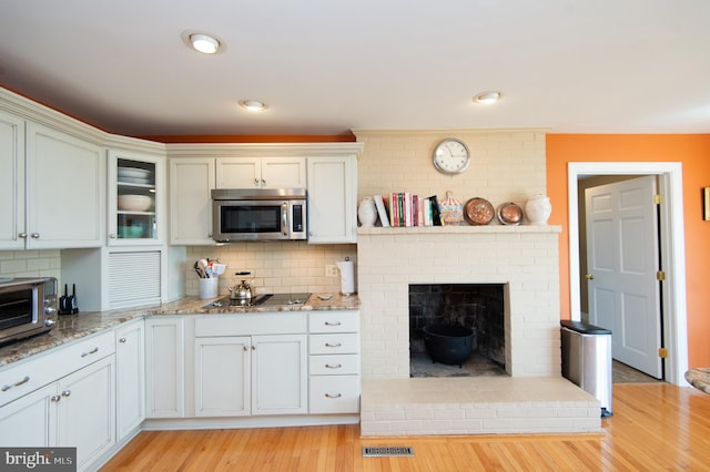 kitchen featuring light hardwood / wood-style flooring, a fireplace, tasteful backsplash, and white cabinetry