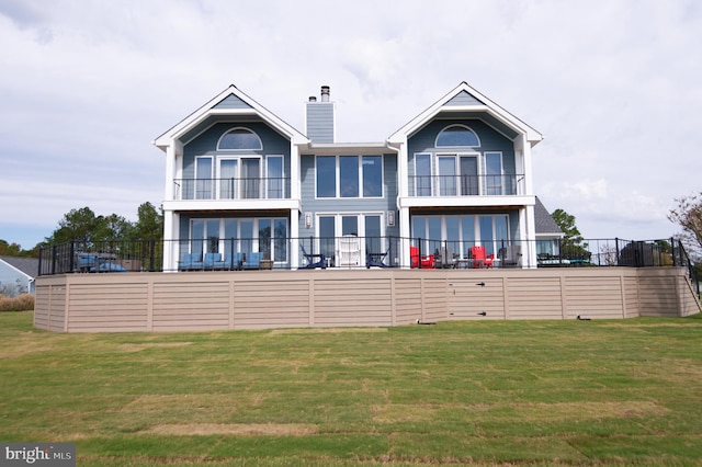 rear view of property featuring a balcony and a lawn