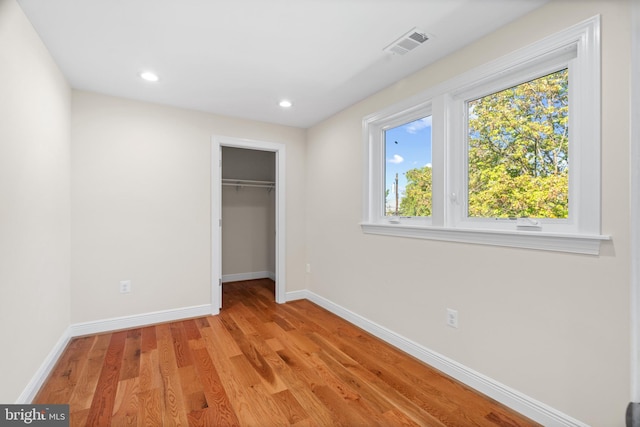 unfurnished bedroom featuring light hardwood / wood-style floors, a walk in closet, and a closet