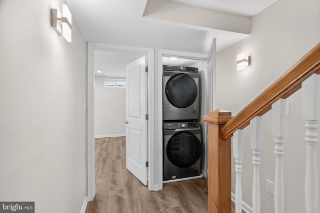 washroom with stacked washer and dryer and light hardwood / wood-style floors