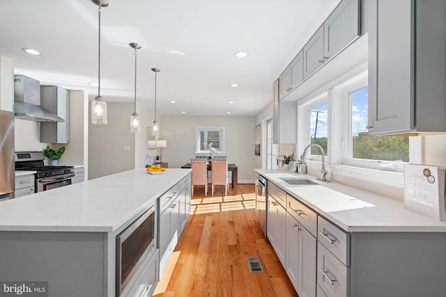 kitchen with wall chimney exhaust hood, gray cabinetry, and stainless steel appliances