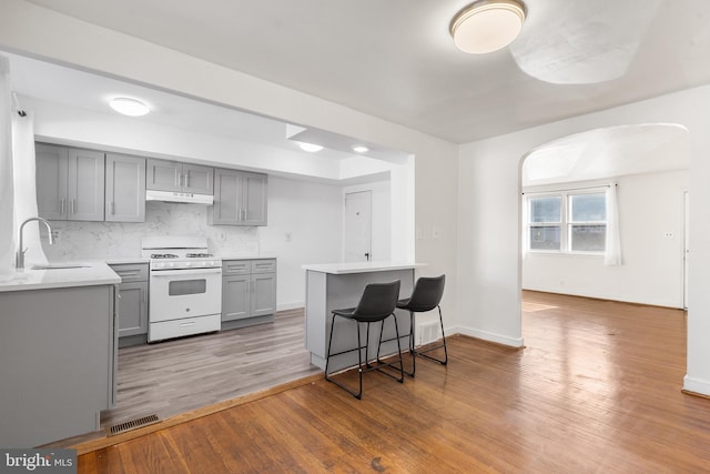 kitchen featuring gray cabinetry, backsplash, white range, sink, and dark hardwood / wood-style flooring