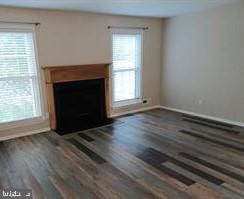 unfurnished living room featuring dark wood-type flooring and a wealth of natural light