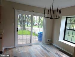 unfurnished dining area with a chandelier and light hardwood / wood-style flooring