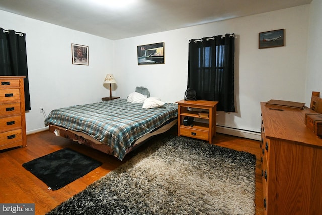 bedroom featuring wood-type flooring and a baseboard heating unit