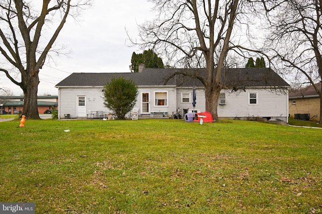 rear view of house featuring a lawn and central AC