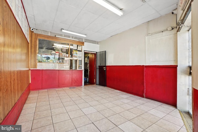 unfurnished room with wooden walls and light tile patterned floors