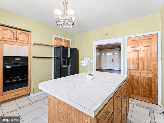 kitchen with a kitchen island, black appliances, a notable chandelier, pendant lighting, and light tile patterned floors