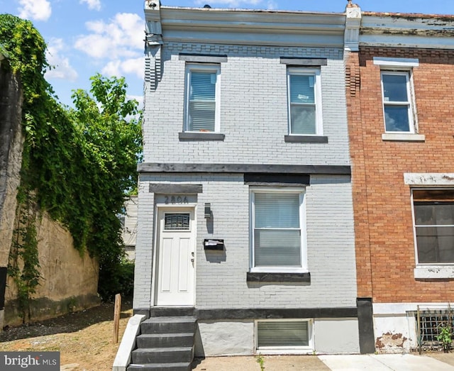 townhome / multi-family property with brick siding, fence, and entry steps