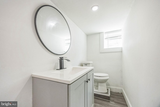 bathroom with wood finished floors, vanity, toilet, and baseboards