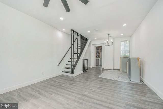 unfurnished living room with light wood-type flooring and ceiling fan with notable chandelier