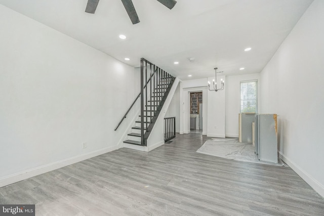 unfurnished living room featuring recessed lighting, stairway, wood finished floors, baseboards, and ceiling fan with notable chandelier