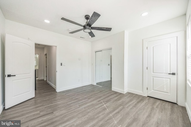 unfurnished bedroom featuring light hardwood / wood-style flooring, a closet, and ceiling fan