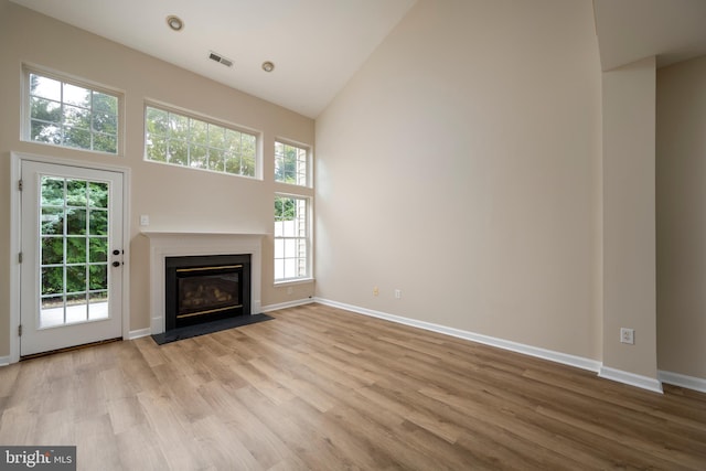 unfurnished living room featuring high vaulted ceiling and light hardwood / wood-style flooring