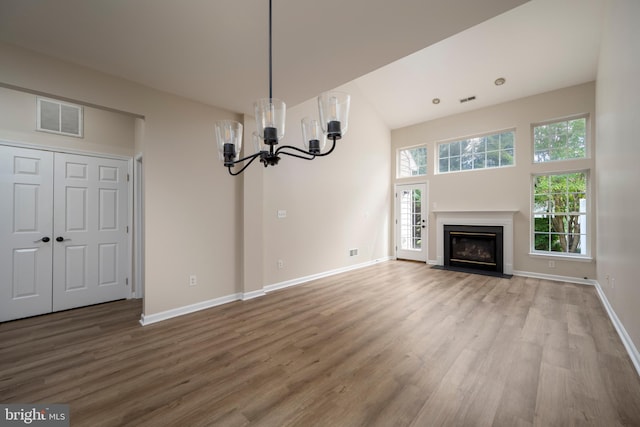 unfurnished living room featuring wood-type flooring, a high ceiling, and a chandelier