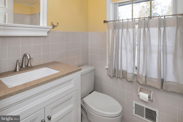 bathroom with tile walls, vanity, and toilet