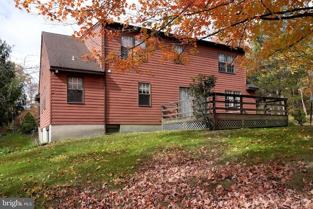 view of property exterior with a wooden deck and a lawn