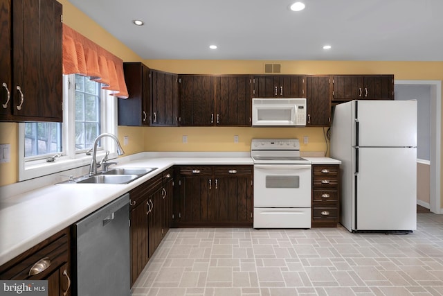 kitchen featuring sink, dark brown cabinets, and white appliances