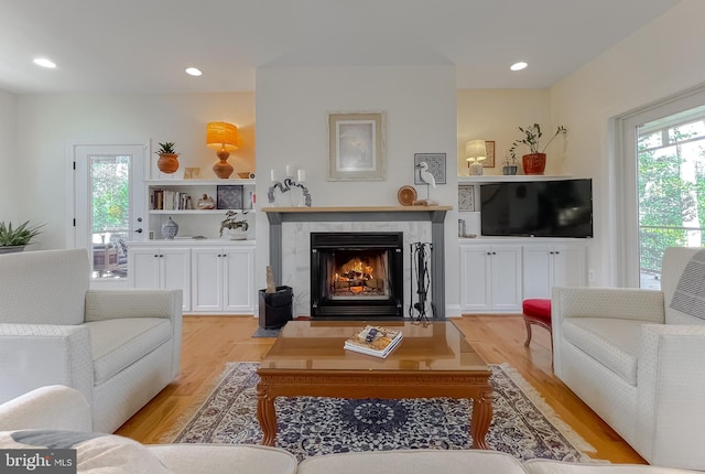 living room with light wood-type flooring and a high end fireplace