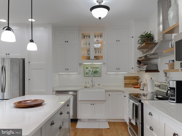 kitchen featuring appliances with stainless steel finishes, white cabinetry, extractor fan, and light hardwood / wood-style floors