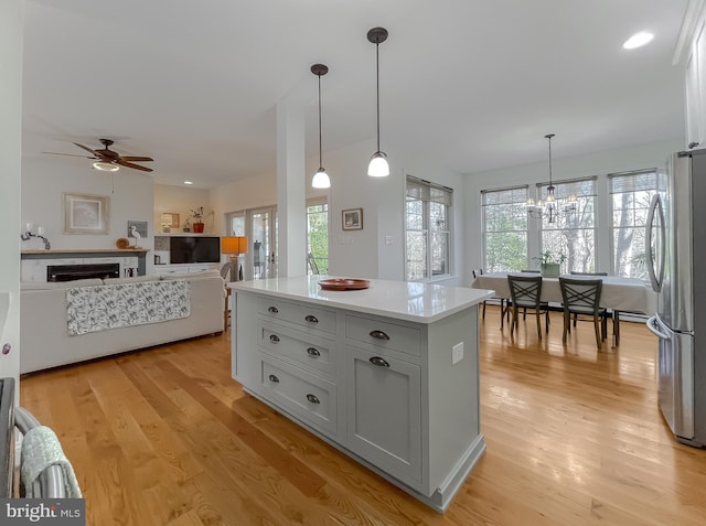 kitchen featuring stainless steel fridge, hanging light fixtures, and light wood-type flooring