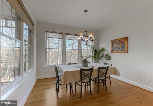 dining space featuring light wood-type flooring and an inviting chandelier