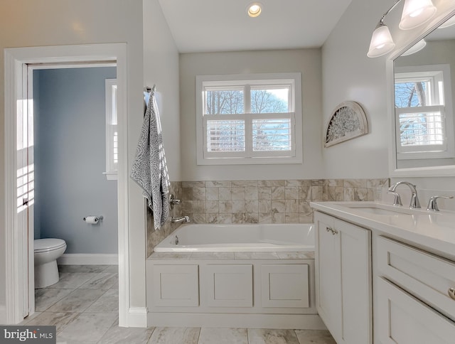 bathroom with a bathing tub, vanity, toilet, and a wealth of natural light