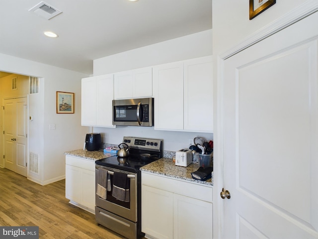 kitchen featuring light hardwood / wood-style floors, white cabinets, stainless steel appliances, and light stone counters