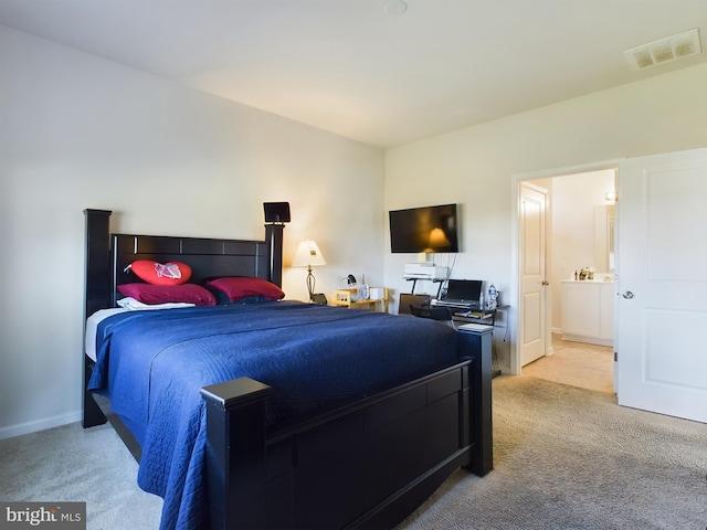 bedroom with ensuite bath and light colored carpet