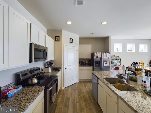 kitchen featuring sink, dark hardwood / wood-style flooring, stainless steel appliances, white cabinets, and light stone counters