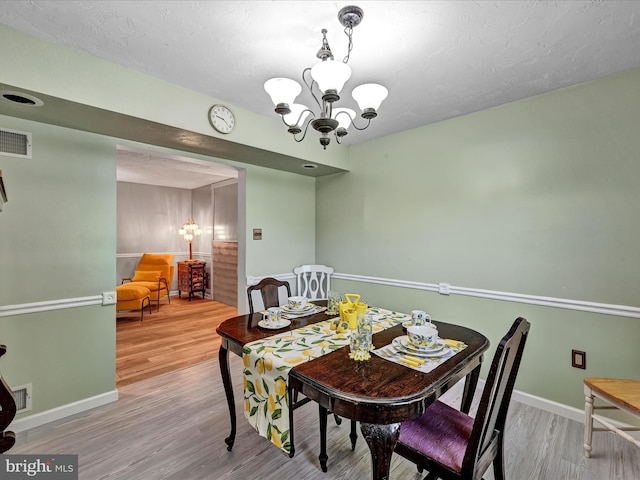 dining room featuring wood-type flooring and an inviting chandelier