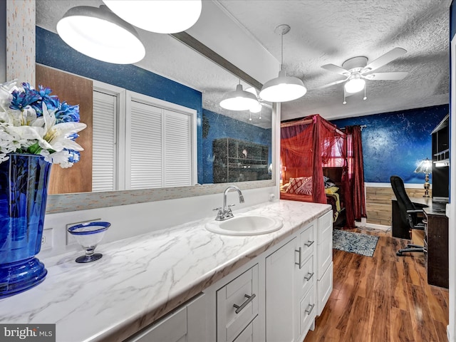 bathroom with vanity, ceiling fan, wood-type flooring, and a textured ceiling