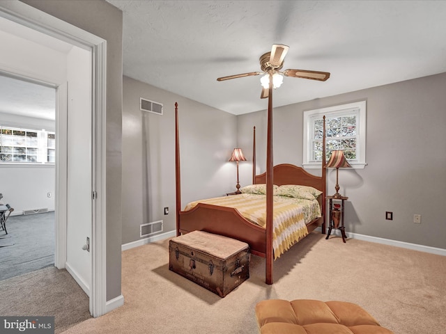 bedroom with ceiling fan, multiple windows, and light colored carpet