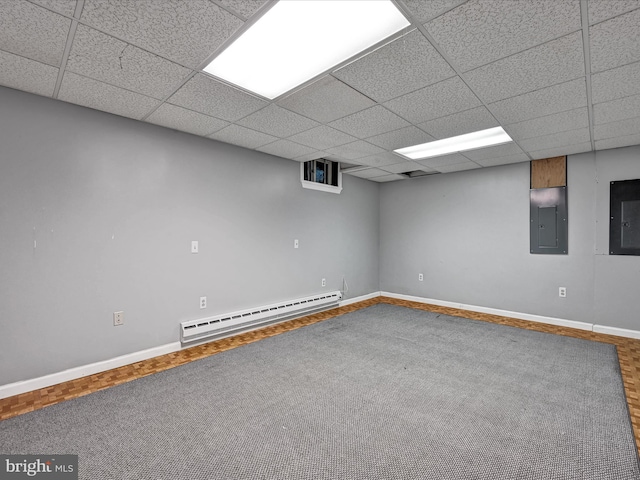 basement featuring a paneled ceiling, hardwood / wood-style flooring, electric panel, and baseboard heating