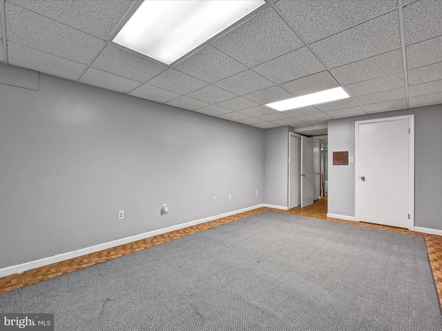 basement featuring a drop ceiling and carpet