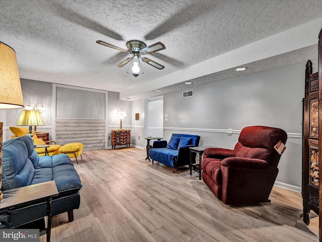 living room featuring a textured ceiling, hardwood / wood-style flooring, and ceiling fan