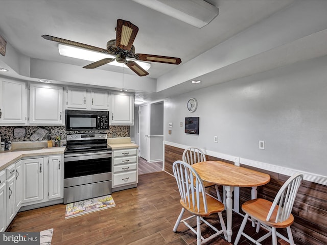 kitchen with stainless steel range with electric cooktop, dark hardwood / wood-style flooring, ceiling fan, white cabinets, and decorative backsplash