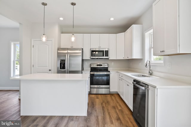 kitchen with appliances with stainless steel finishes, a kitchen island, sink, white cabinetry, and decorative light fixtures