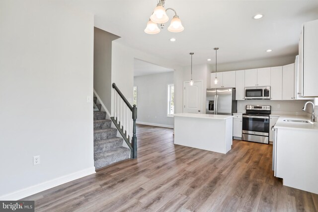 kitchen with stainless steel appliances, a center island, pendant lighting, sink, and white cabinetry