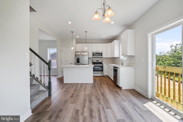 kitchen featuring white cabinets, stainless steel appliances, a kitchen island, and hanging light fixtures