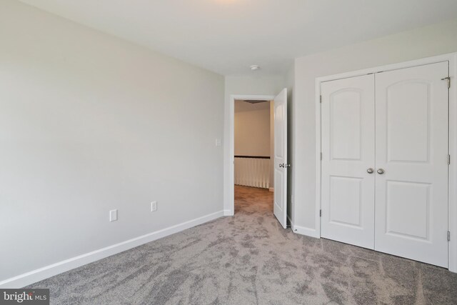 unfurnished bedroom featuring a closet and light colored carpet