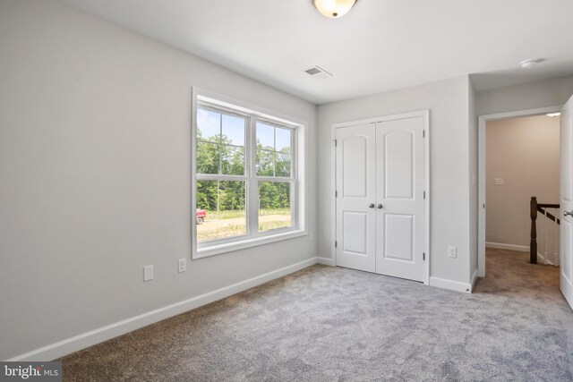 unfurnished bedroom featuring light colored carpet and a closet