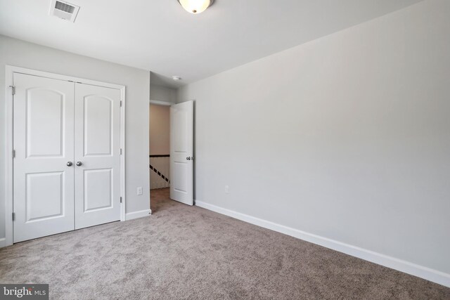 unfurnished bedroom with a closet and light colored carpet