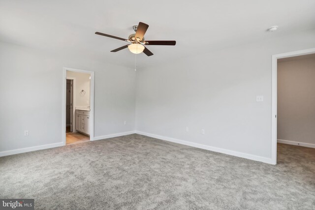 interior space with ceiling fan, light colored carpet, and ensuite bath