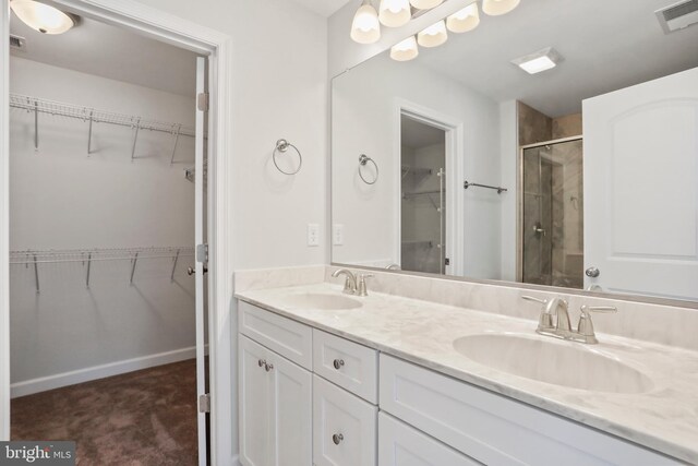 bathroom featuring a shower with door and vanity